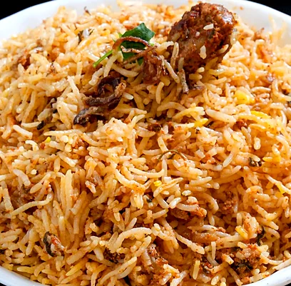 Close-up of biryani rice with a piece of meat, fried onions and coriander