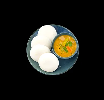 Four idli on a blue plate with a bowl of sambar
